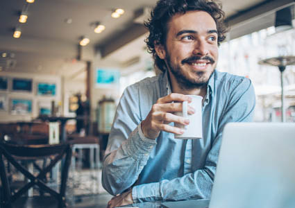 man on his laptop drinking a cup of coffee